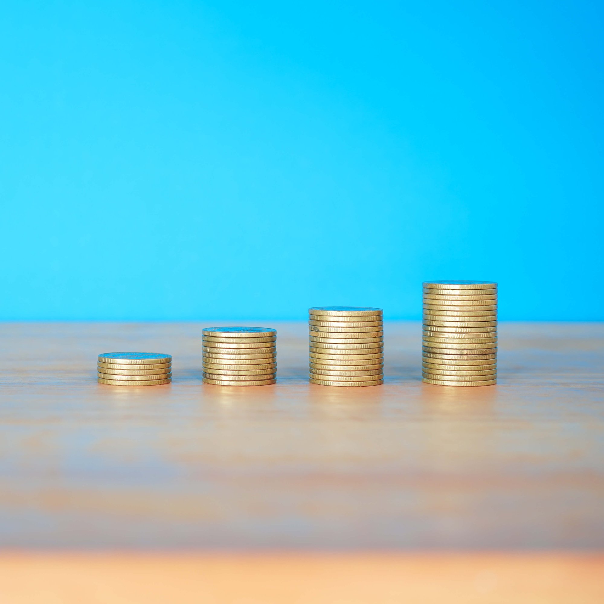stacks-of-gold-money-coin-on-wooden-desk-with-blue-2024-12-07-04-52-42-utc (1)