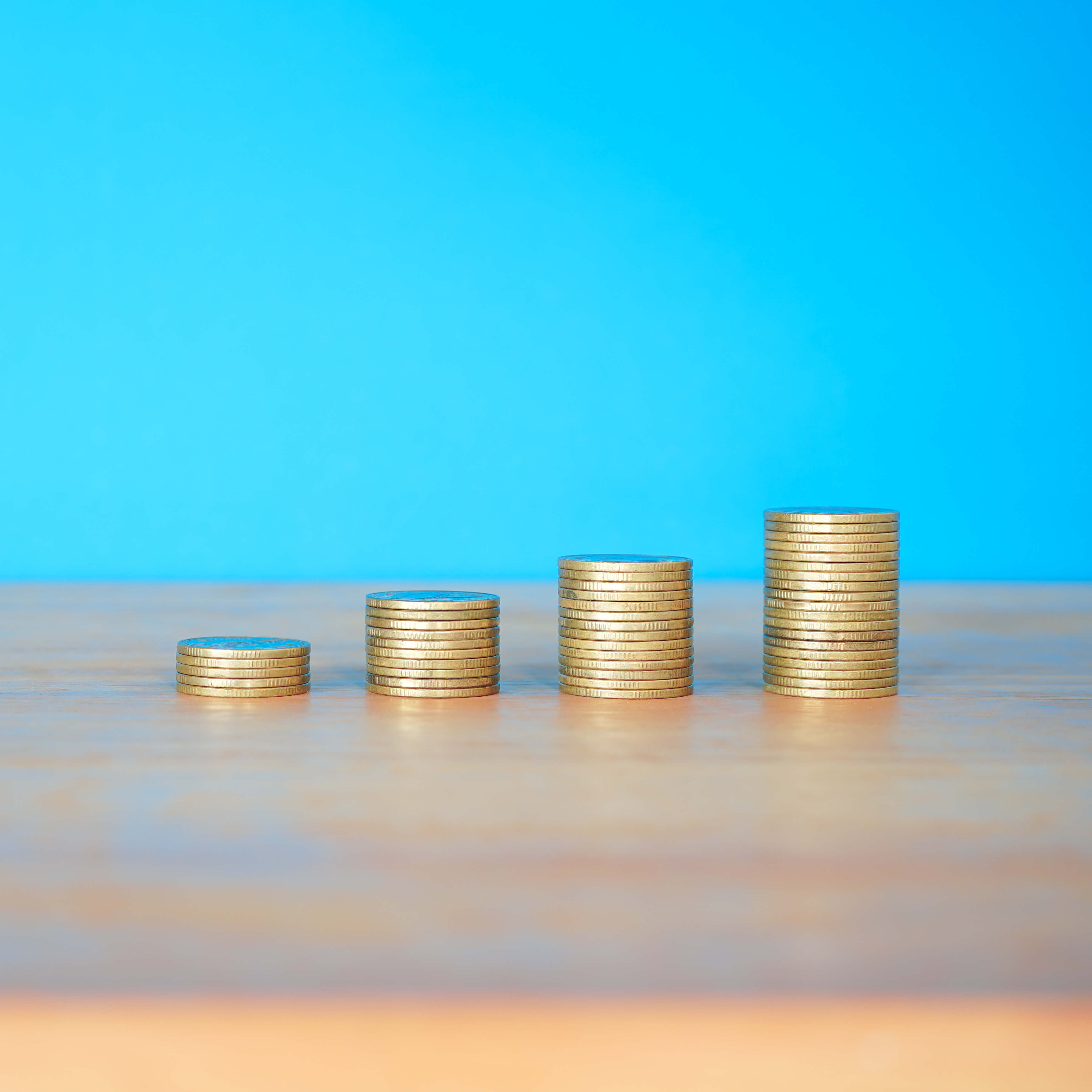 stacks-of-gold-money-coin-on-wooden-desk-with-blue-2024-12-07-04-52-42-utc (1)
