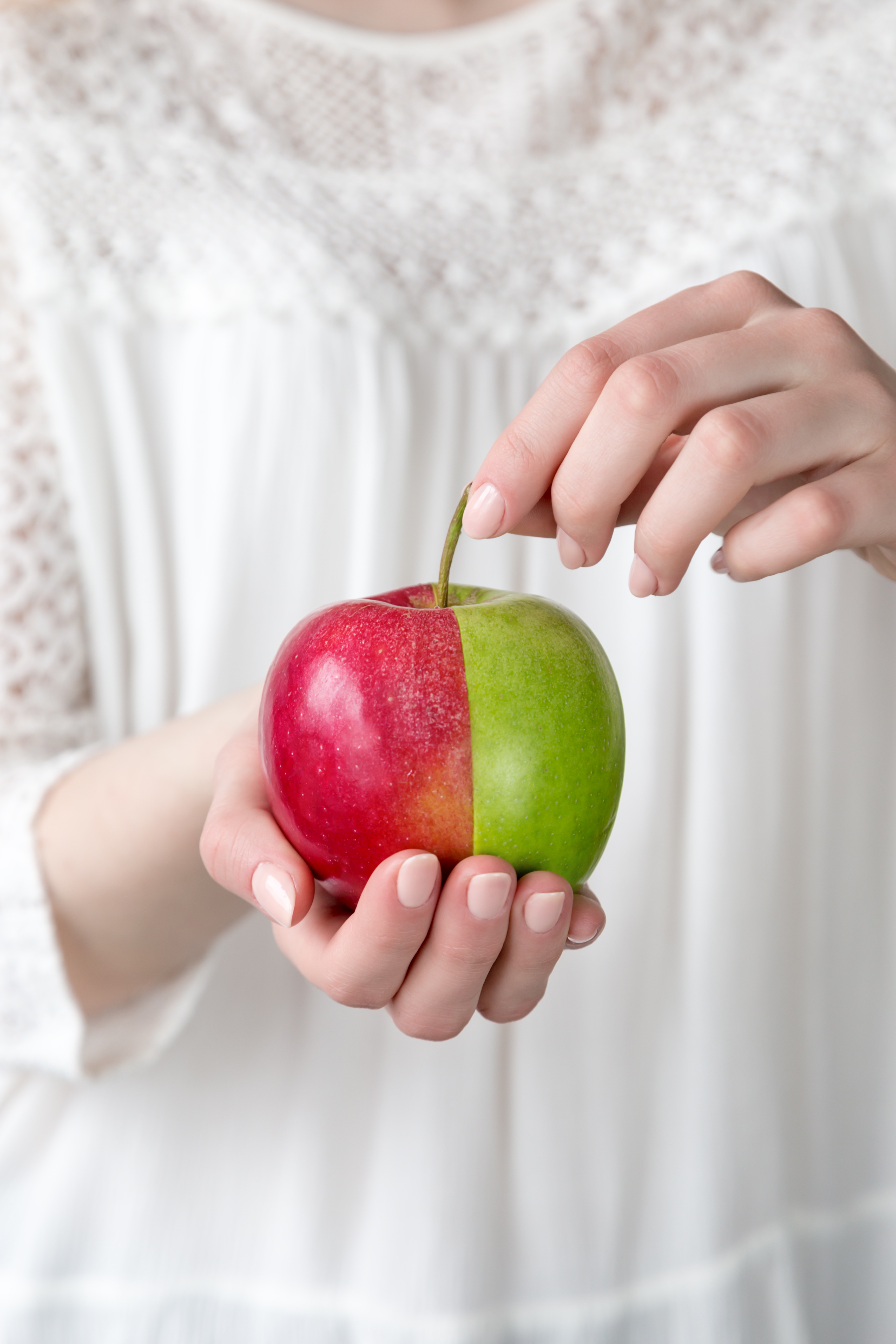 female-hands-hold-an-apple-consisting-of-red-and-g-2025-03-08-23-44-03-utc